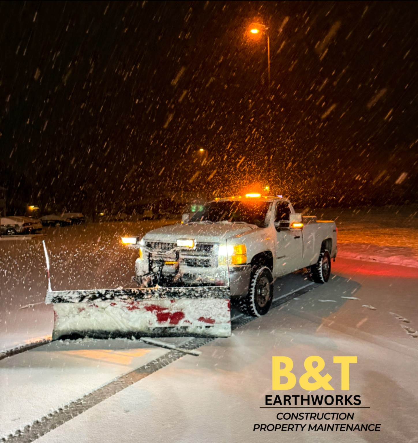 BW Excavation snowplow clearing a parking area during active snowfall